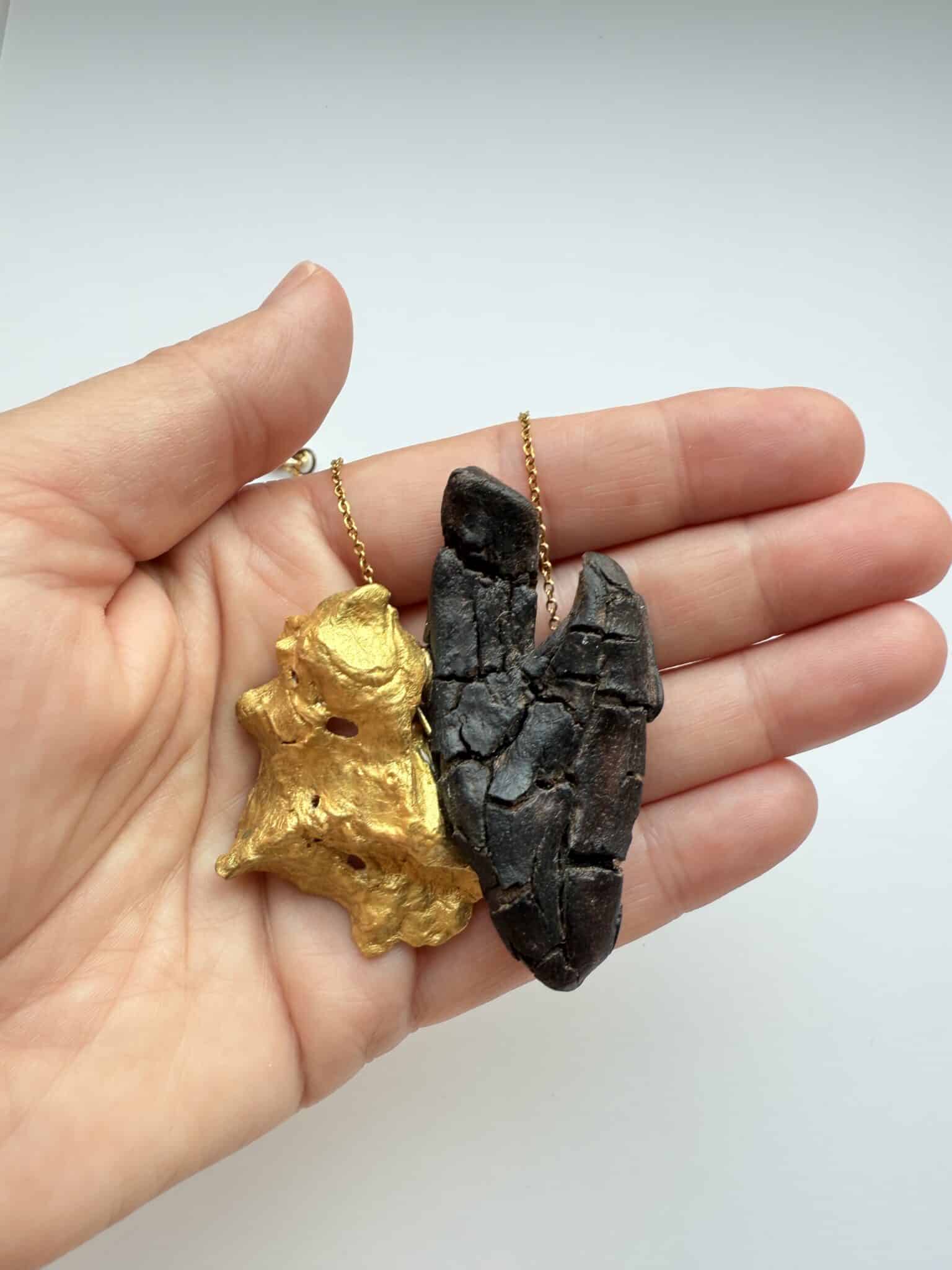 Colgante artesanal creado con madera del mar traida por las mareas y oscura y agrietada en forma de corazón y concha de ostra dorada. cadena dorada de acero inoxidable.