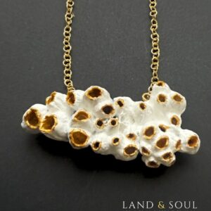 “Collar de 9 cm elaborado con barnacles unidos con resina, piezas de cerámica marina y cristales del mar, sobre cadena dorada – diseño exclusivo Land & Soul.”