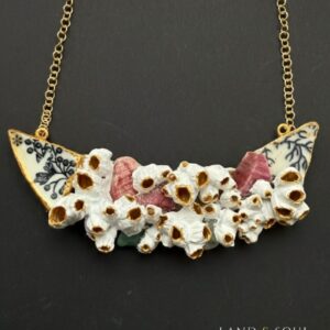 “Collar de 9 cm elaborado con barnacles unidos con resina, piezas de cerámica marina y cristales del mar, sobre cadena dorada – diseño exclusivo Land & Soul.”