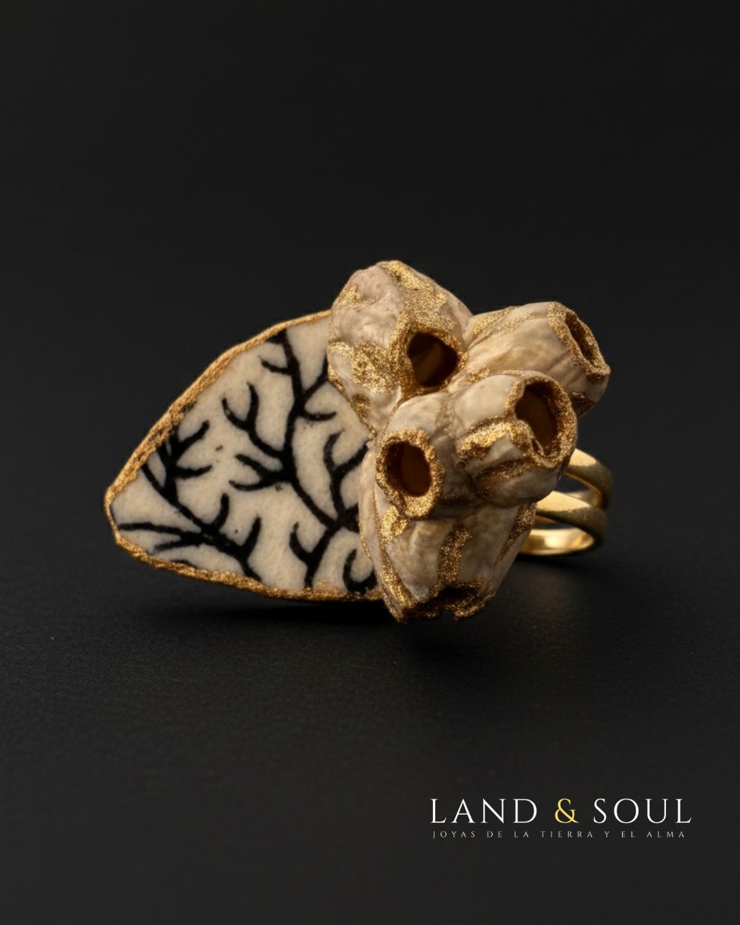 «Anillo artesanal con barnacles y cerámica marina negra, pieza única de Land & Soul sostenida con la mano»