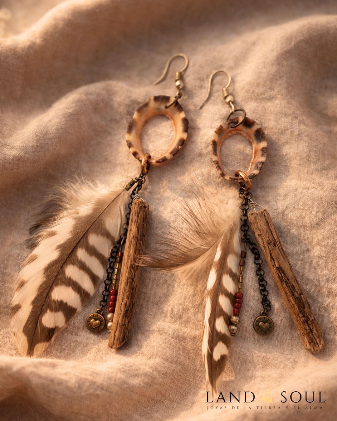 Pendiente artesanal y exclusivo creado con plumas recolectadas de forma manual de entornos como bosques, paseos y otros espacios naturales. En este caso desconozco a la especie a la que pertenecen. Son unas plumas tupidas y recuerdan las tribus índias.  Creados con dos plumas similares, una tira de pedrería de cristal en tonos dorados y rojizos, madera del mar traída por las mareas y la concha de una la papa erosionada que hace de enlace de todos ellos. Unos pendientes únicos de aspecto tribal con mucho carácter.